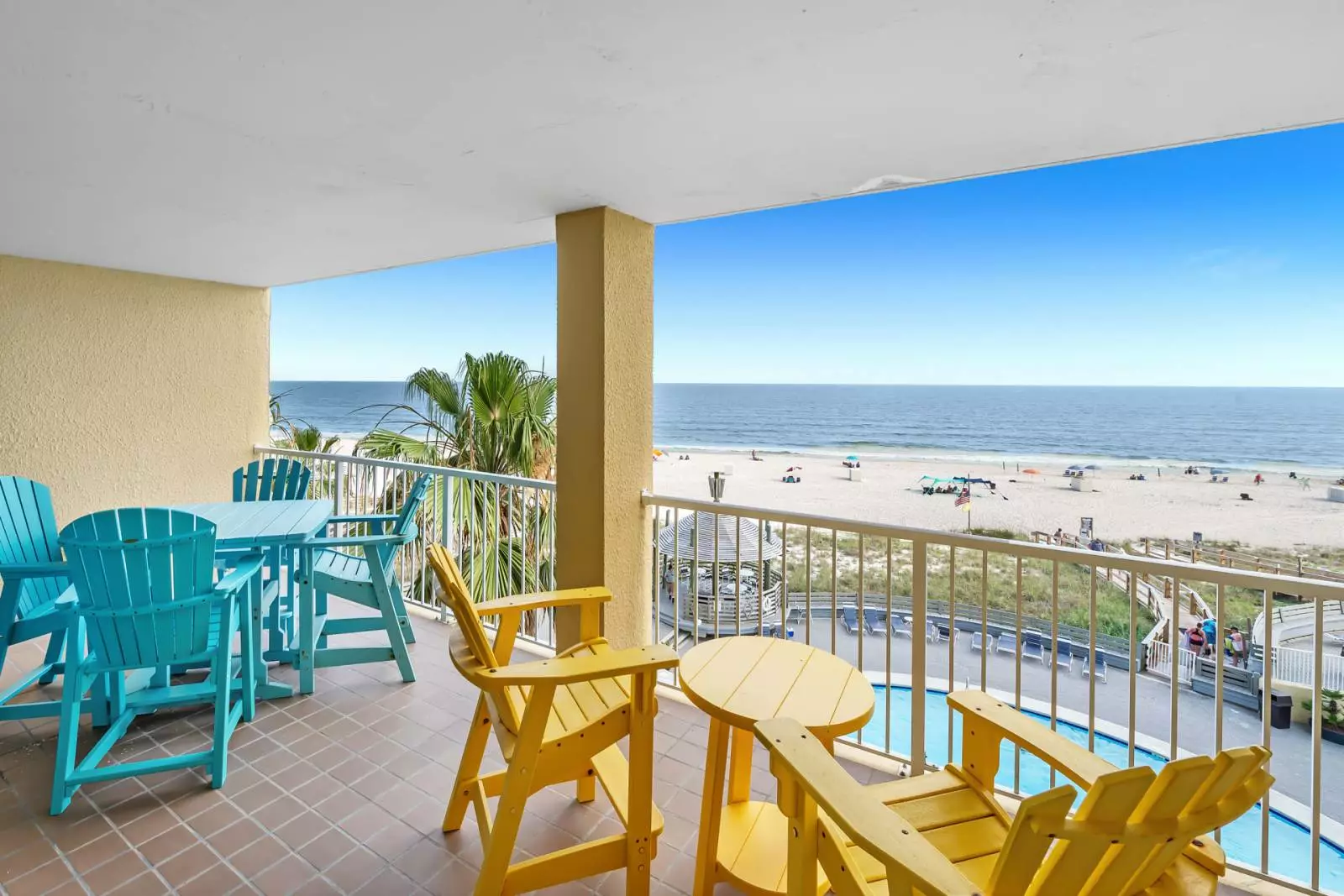 chairs and table on balcony overlooking pool and beach