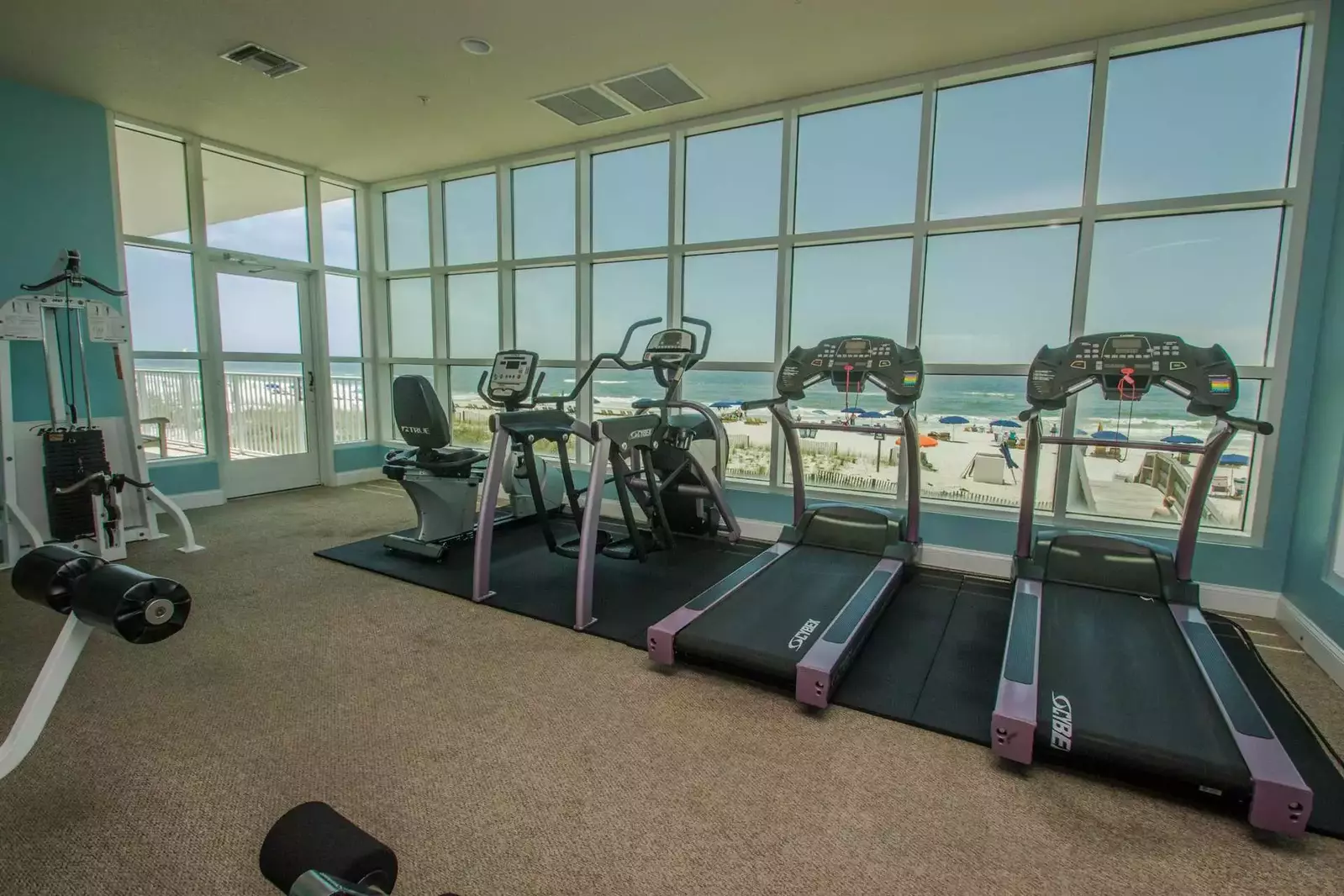 Community fitness center with cardio equipment overlooking beach and Gulf