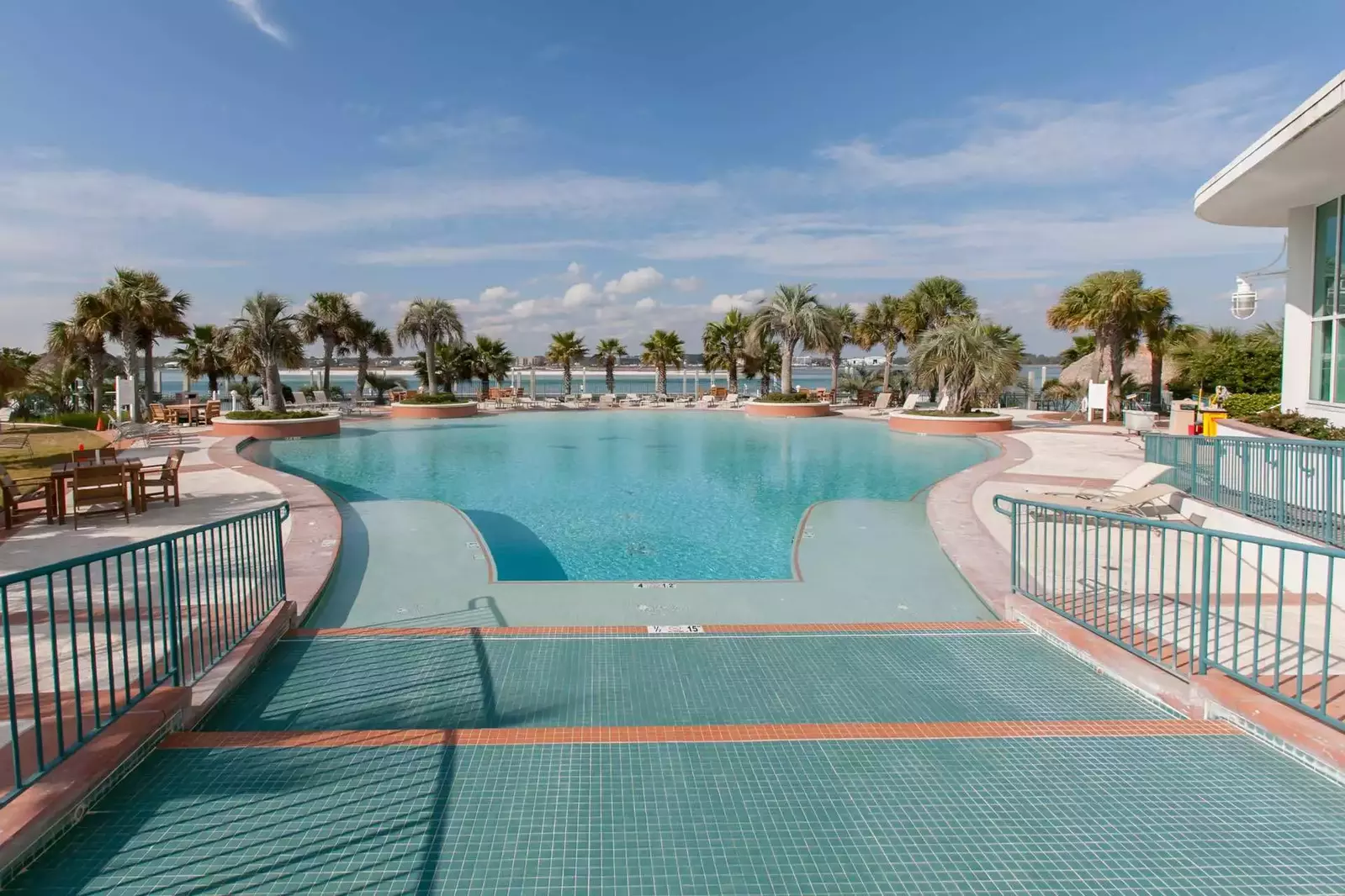 Community pool with lounge chairs and tropical foliage