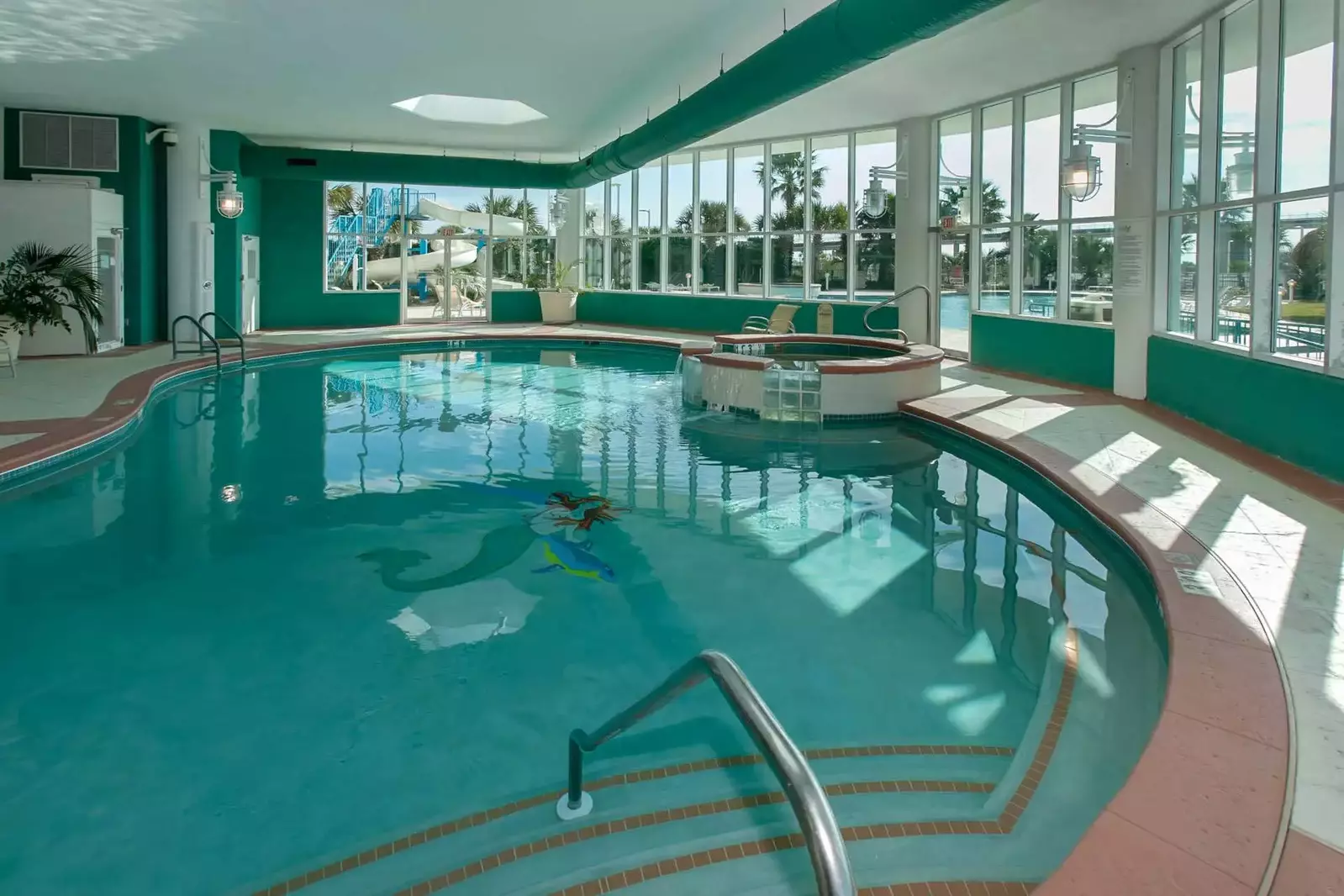 Heated indoor pool with hot tub looking towards waterslide