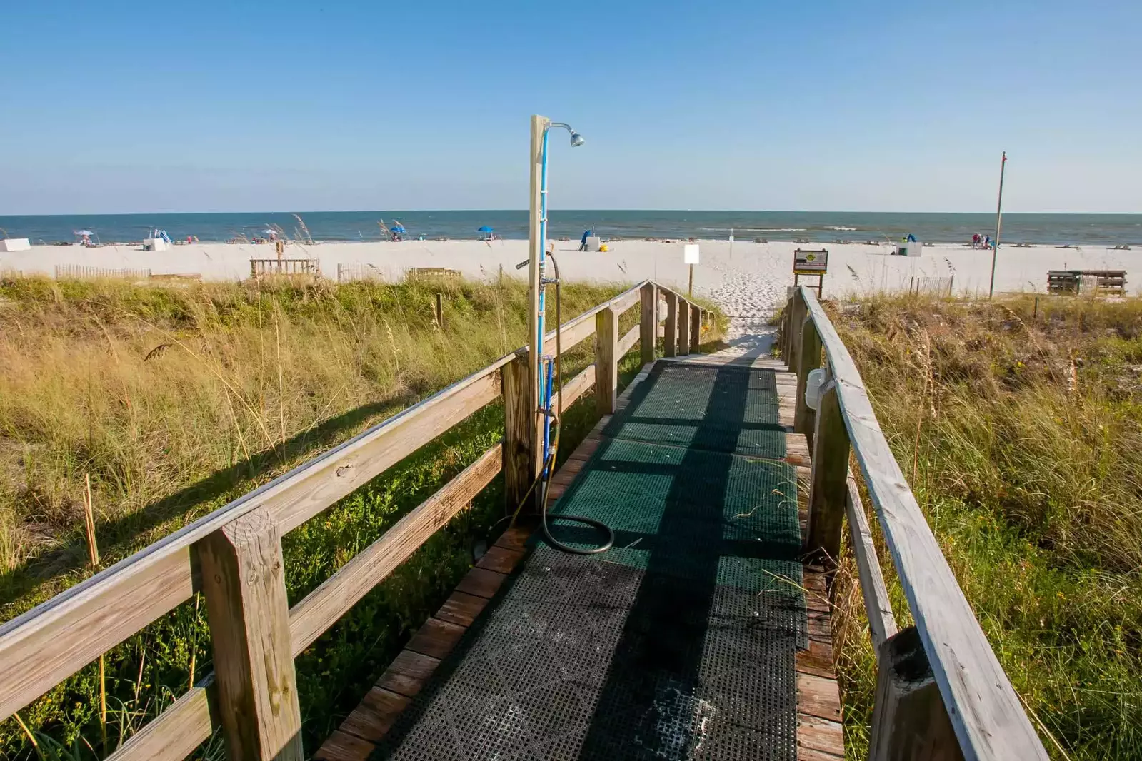 Community boardwalk with outdoor shower leading to beach and Gulf