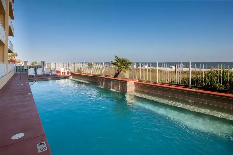 Community pool with lounge chairs overlooking the beach and the Gulf
