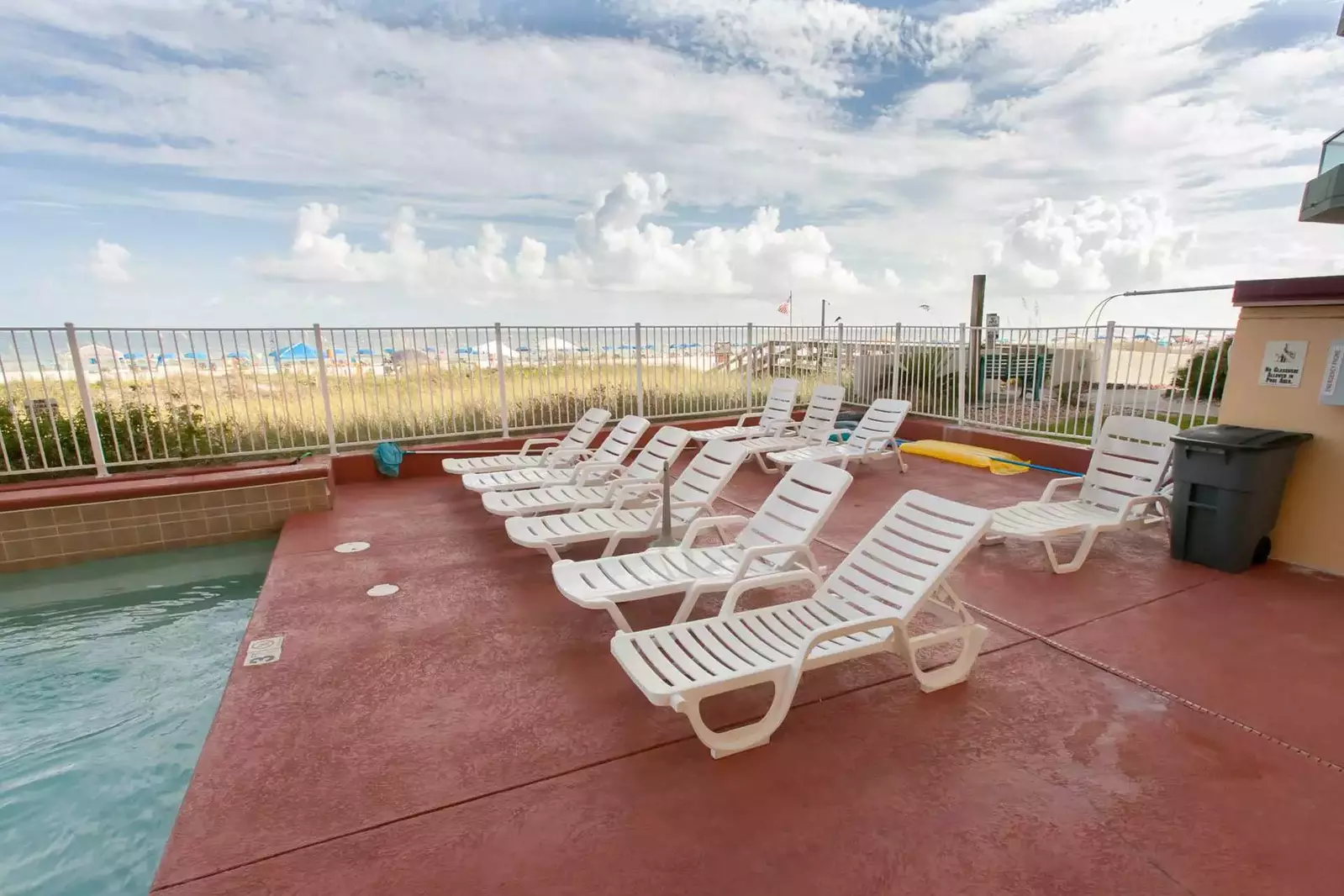 Lounge chairs at the community pool with beach and Gulf in background