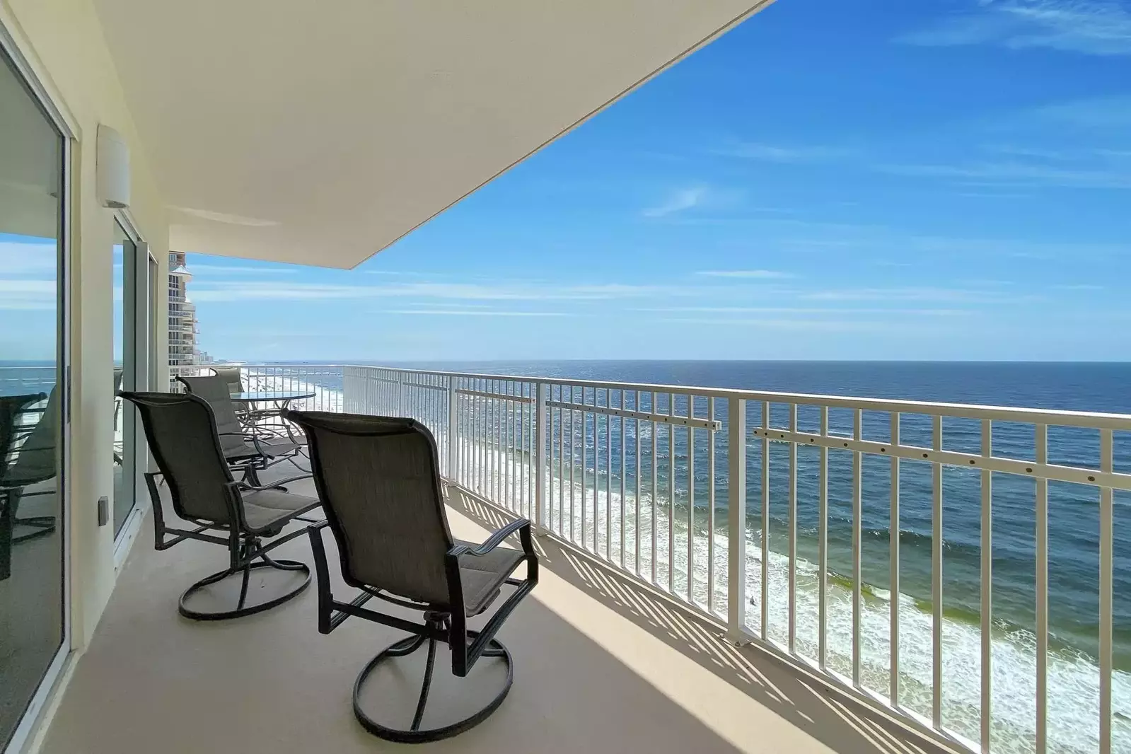 Gulf-front views from the balcony, with chairs to relax in and a table for dining.