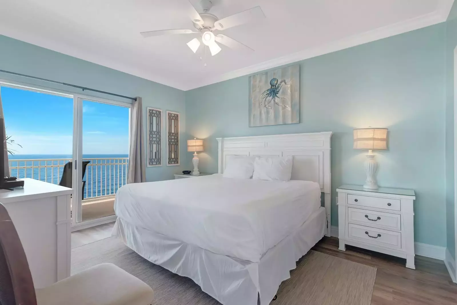 Primary bedroom with a king bed, dual nightstands, direct balcony access, and a flat screen TV.