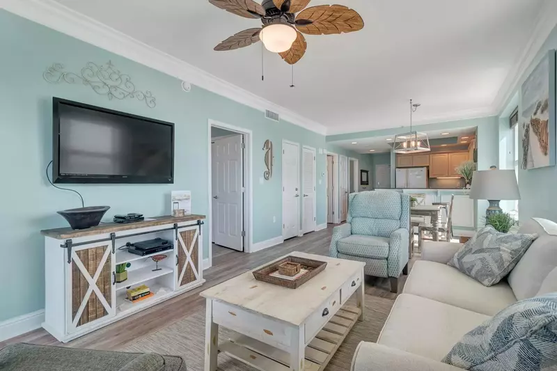 View of the living area featuring a sofa sleeper, wall mounted 55" TV, and lovely Coastal decor.