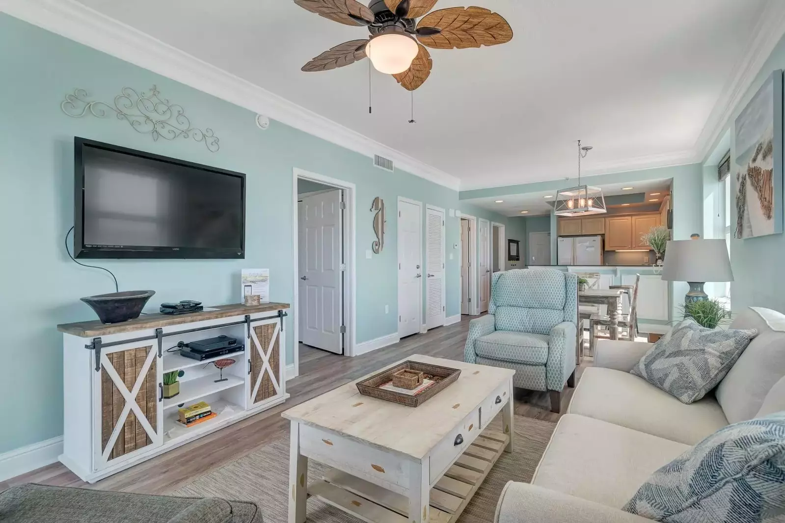 View of the living area featuring a sofa sleeper, wall mounted 55" TV, and lovely Coastal decor.