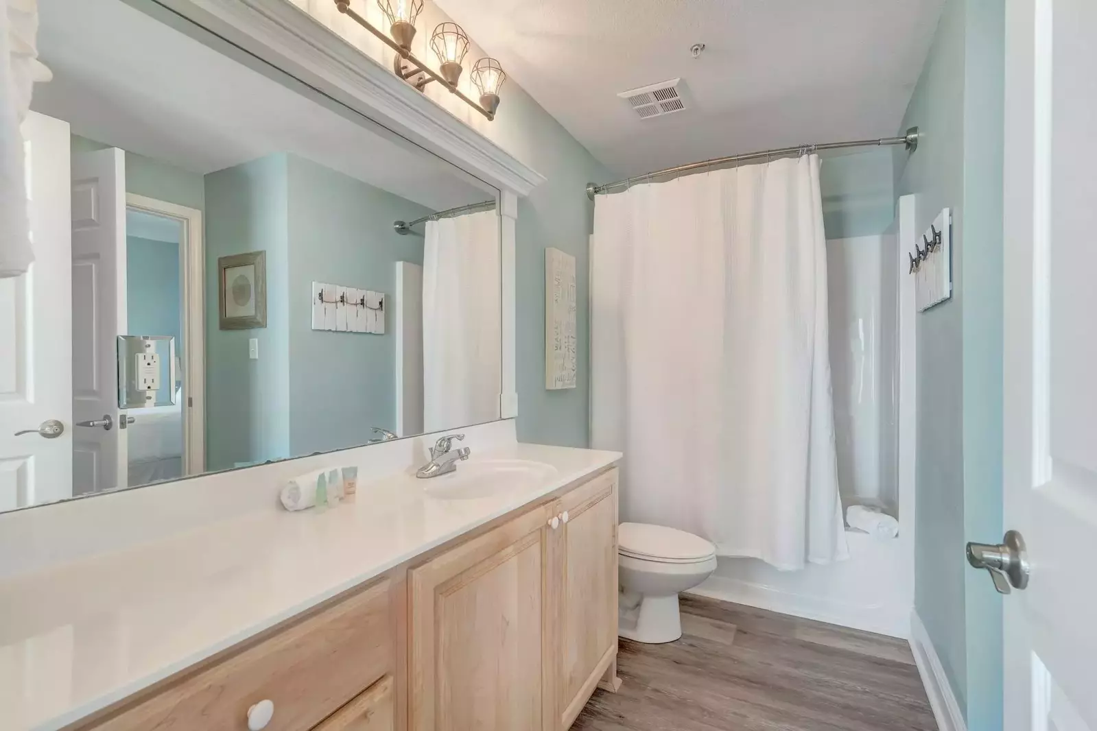 Guest bath with large mirror and shower/tub combo. Access from hallway and guest bedroom.