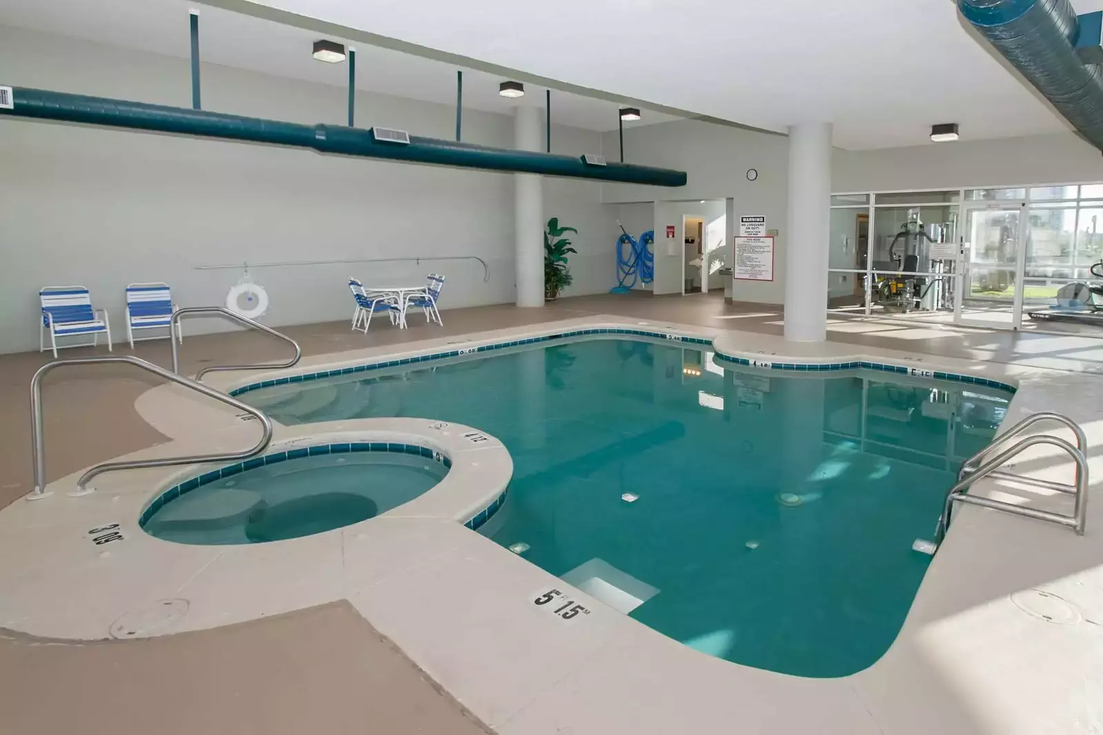 Indoor pool and hot tub with lounge chairs