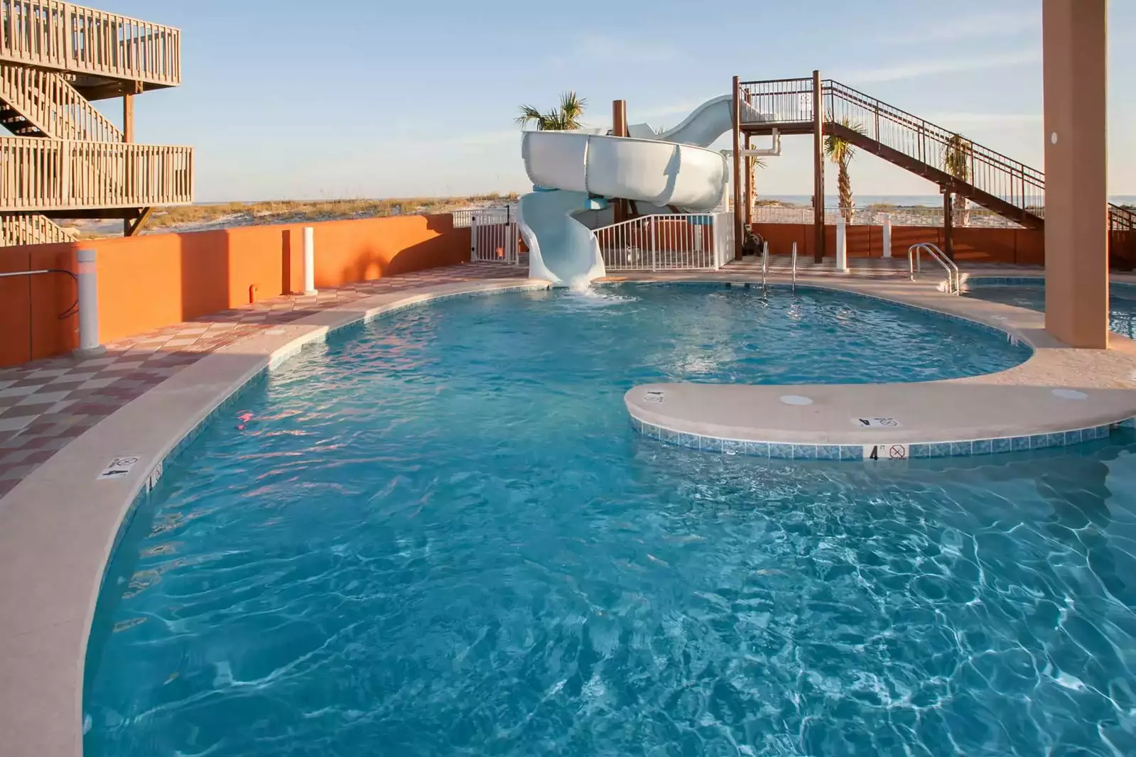 Pool and waterslide with view of beach and Gulf