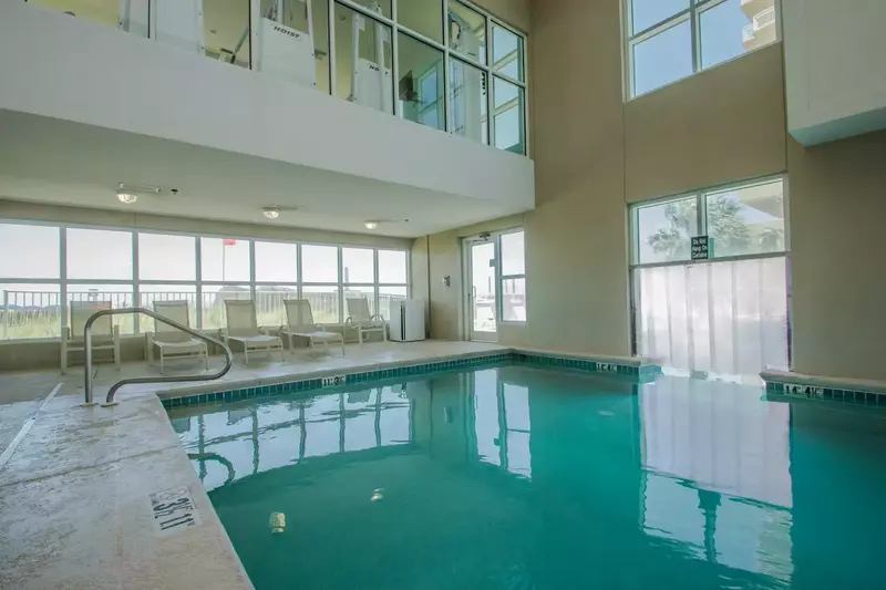 Indoor pool w/lounge chairs and views towards beach.