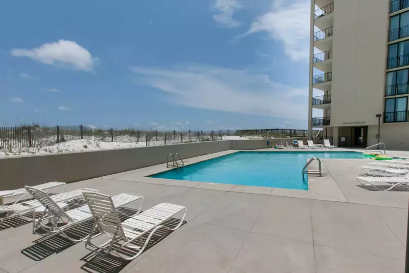 Community pool w/lounge chairs overlooking the beach and Gulf