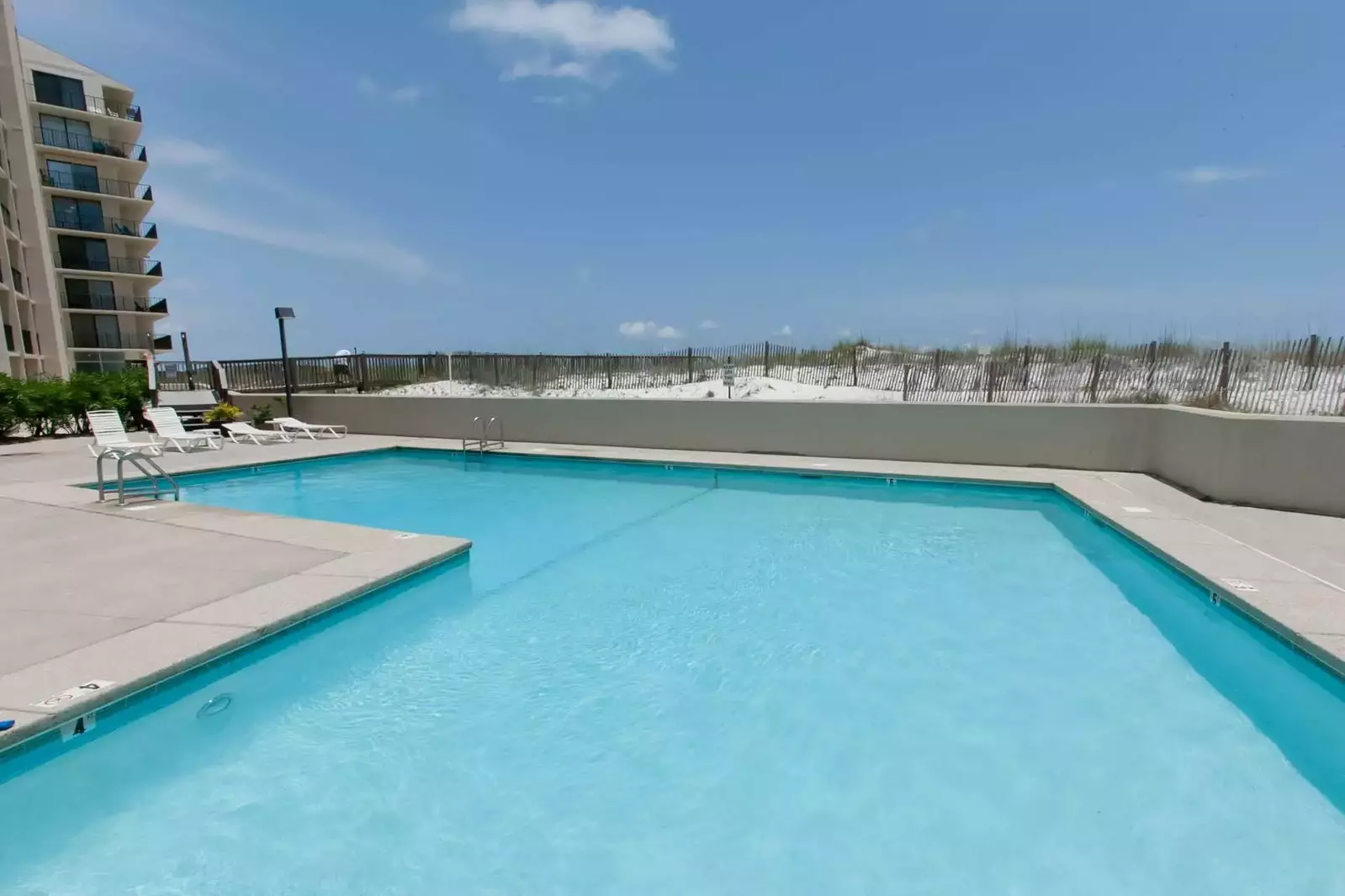 Community pool w/lounge chairs overlooking the beach and Gulf