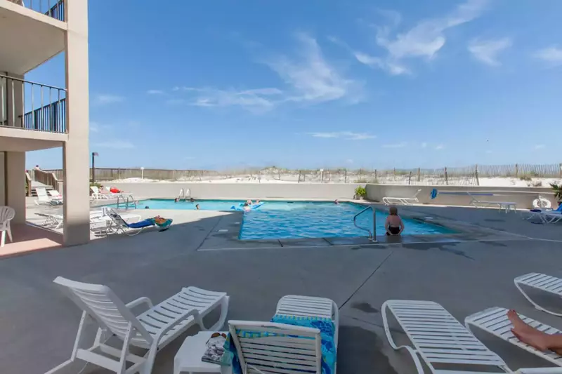 Community pool w/lounge chairs overlooking the beach and Gulf