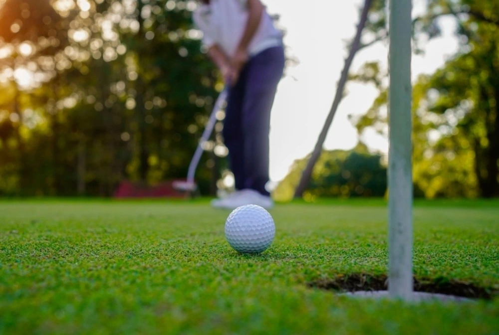 golf ball rolling toward hole