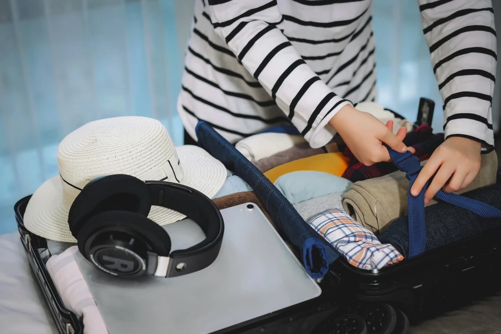 packing suitcase for vacation with rolled clothes
